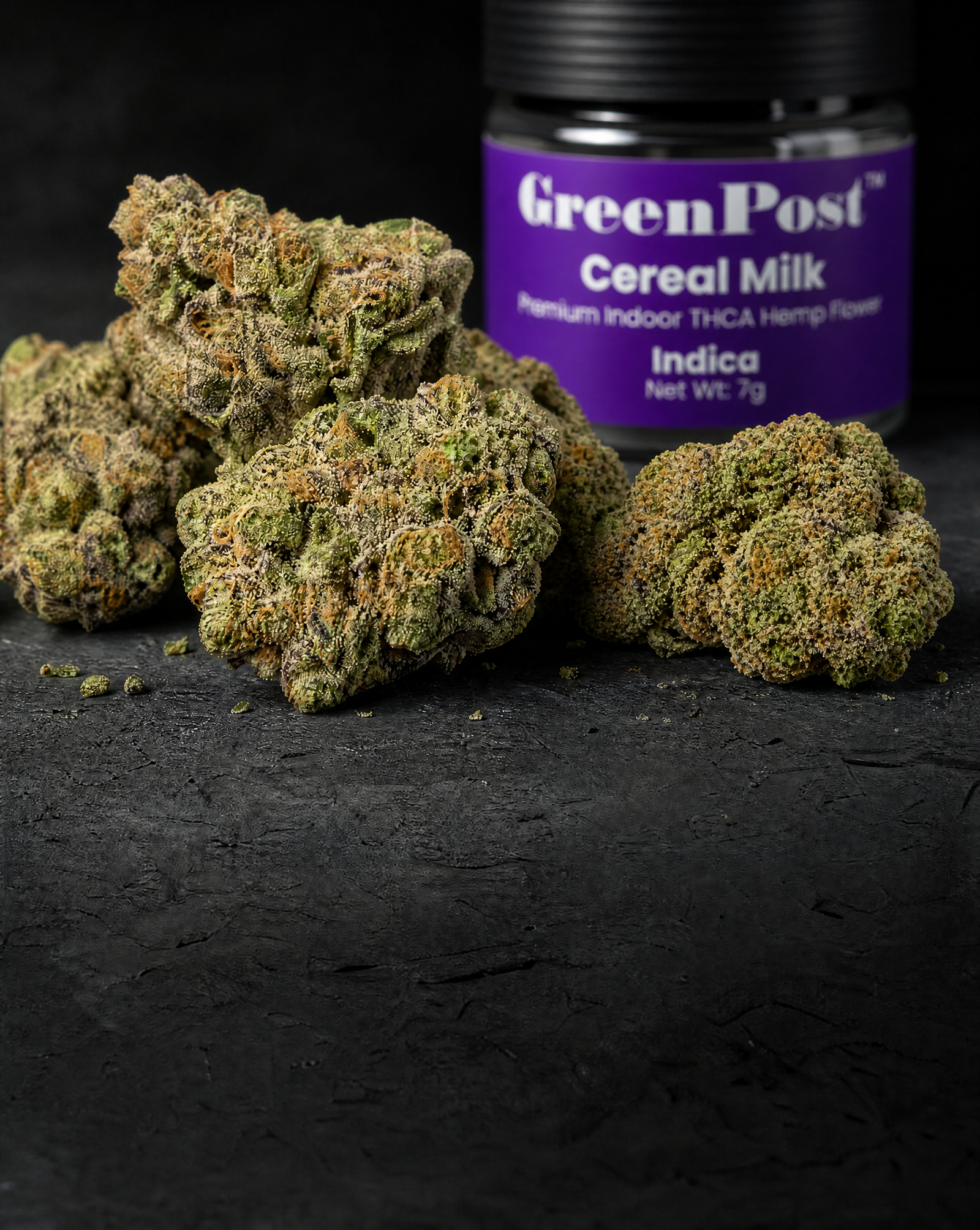 Close-up of premium Cereal Milk indoor THCA flower buds displayed in front of a GreenPost Cereal Milk 7g jar on a dark stone surface.